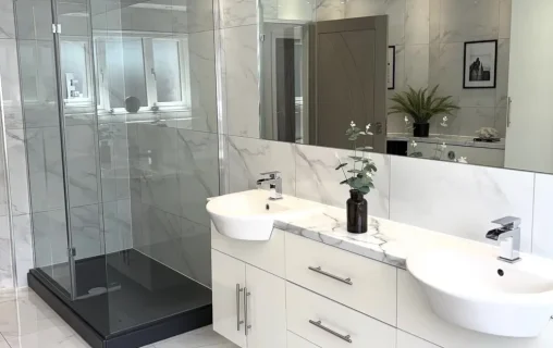 White bathroom with a double vanity and glass shower enclosure