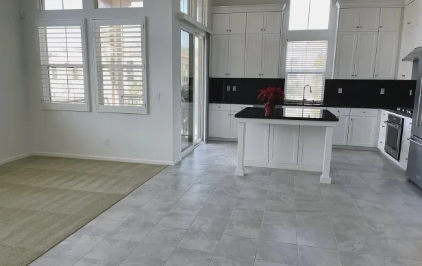 Empty kitchen and adjoining living area with tile and carpet flooring