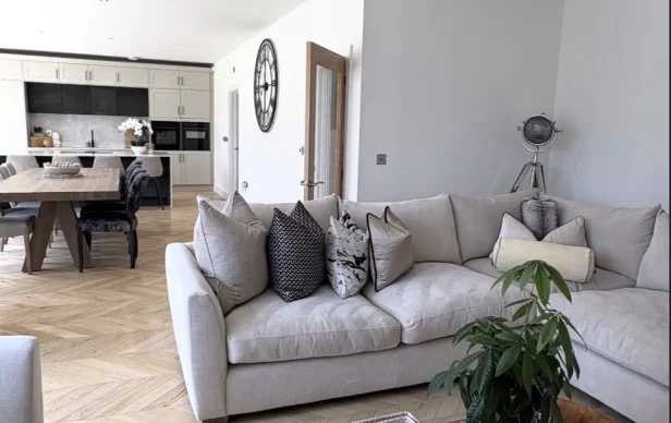Living room with a gray sectional, wood flooring and an open-plan kitchen